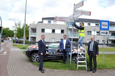 Zu sehen sind die Beteiligten beim Reinigen eines Radweg-Schildes